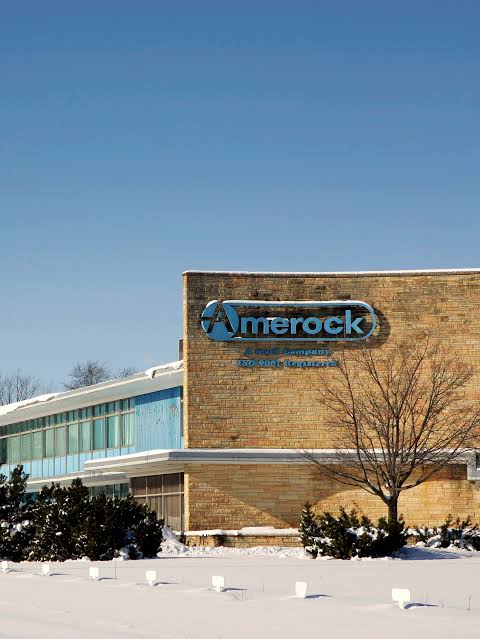 The Amerock plant in Rockford, Illinois, under snow — the blue oval reading "a Newell company · ISO 9001 Registered." The same site has made cabinet hardware for generations, through every owner the brand has had.
